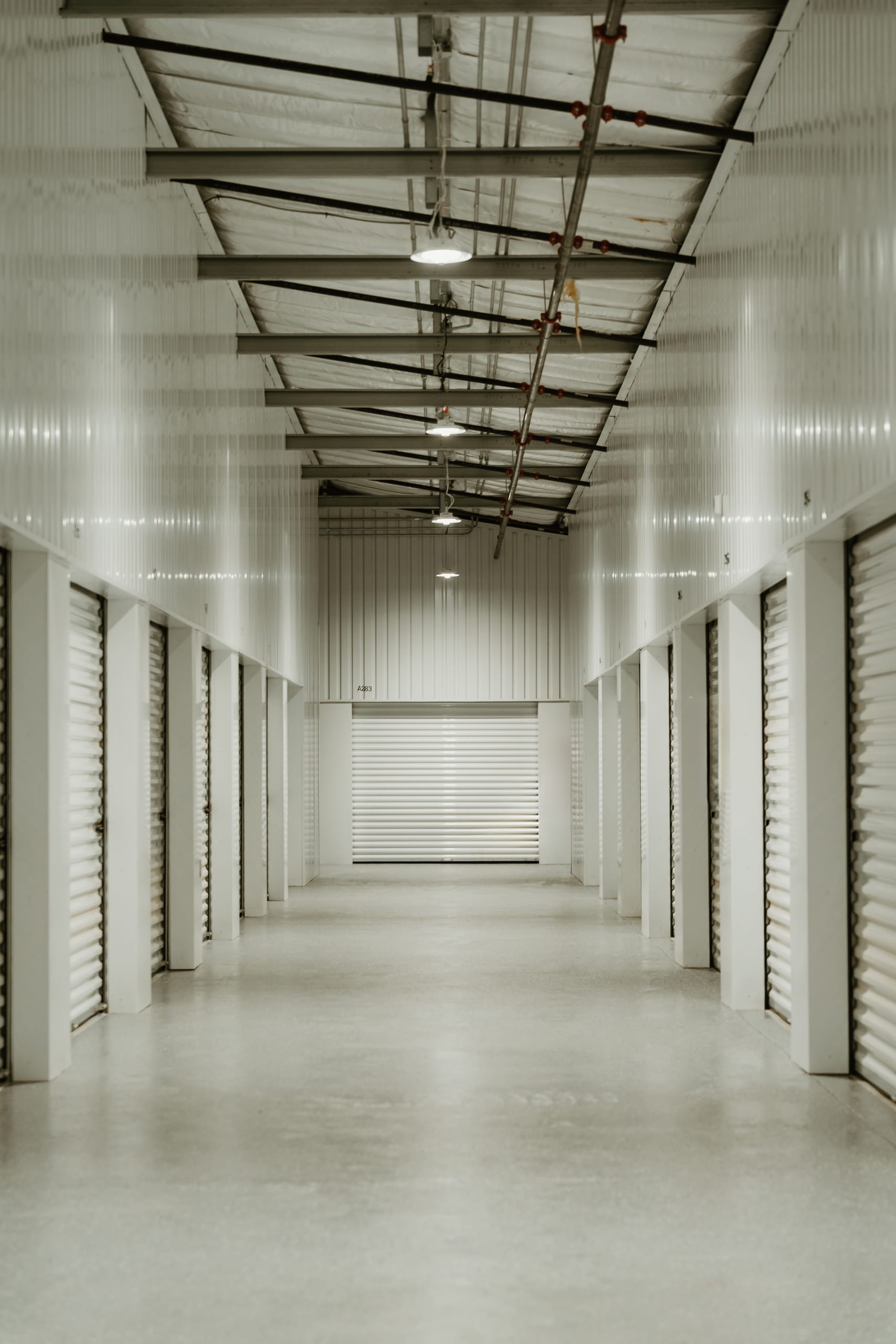 Bright interior climate-controlled hallway at Baucom with white corrugated walls, roll-up doors, and polished concrete floors