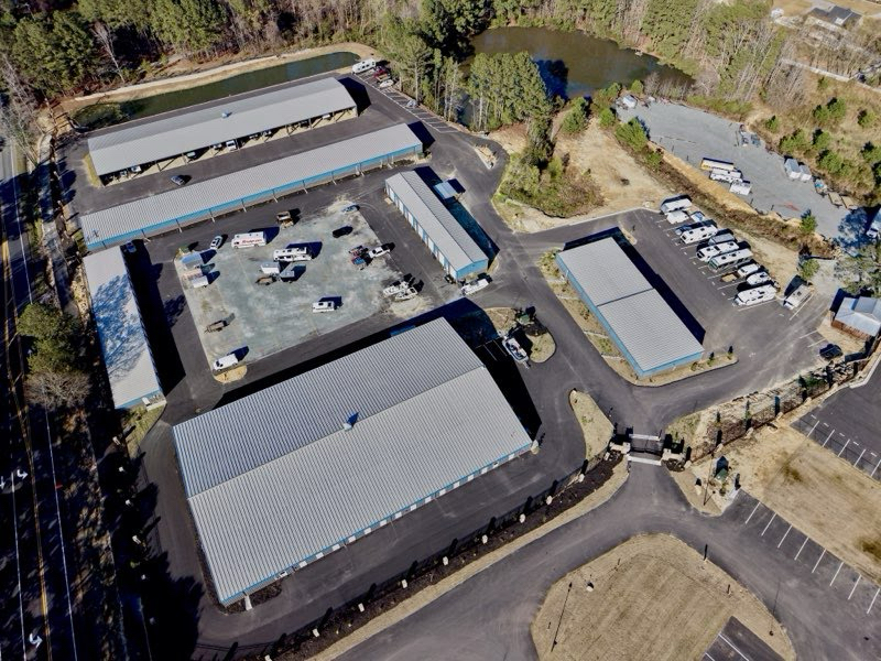 High aerial of the entire Baucom property showing the layout of buildings, RV parking, and two ponds